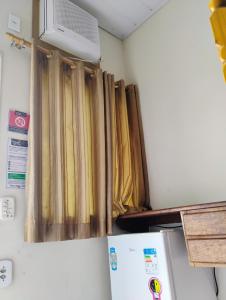 a kitchen with curtains on the wall and a refrigerator at Pousada SolMar in Caraguatatuba