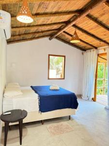 a bedroom with a large bed with a blue blanket at Casa deck Caraíva in Caraíva