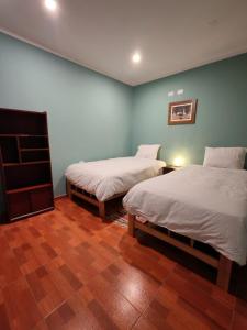 two beds in a room with blue walls and wooden floors at Catag Wasi Casa hospedaje in Cajamarca