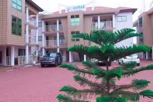 a palm tree in a parking lot in front of a building at JANNAH VILLAS - GHANA in Adentan