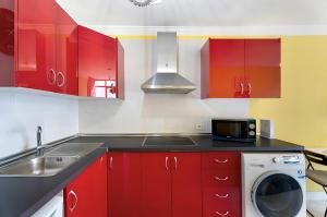 eine Küche mit roten Schränken und einer Waschmaschine in der Unterkunft Apartamento en Calle Heraclio Sánchez in La Laguna