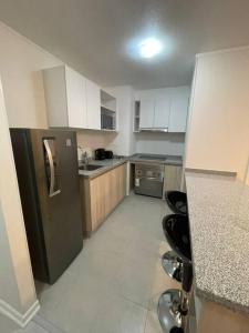 a kitchen with a black refrigerator and white cabinets at Herradura Vista II in Coquimbo +2 photos