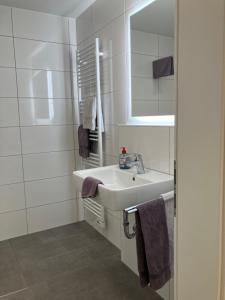ein weißes Badezimmer mit Waschbecken und Spiegel in der Unterkunft Haus Etzold in Norderney