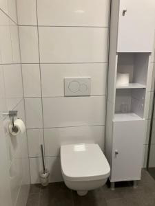 ein weißes Bad mit einem WC und einer Rolle Toilettenpapier in der Unterkunft Haus Etzold in Norderney + 12 Fotos