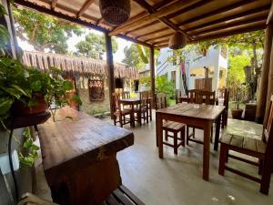 an outdoor patio with wooden tables and chairs at Suítes Aracuã in Caraíva