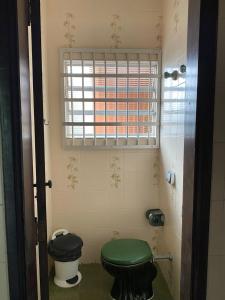 a bathroom with a green toilet and a window at Casa 50m da praia - Enseada/Guarujá in Guarujá
