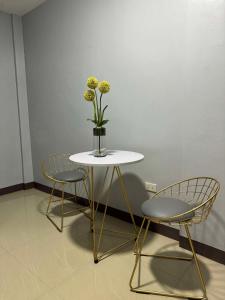 a table with two chairs and a vase with flowers at JP Suites & Residences in Tayabas
