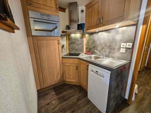a small kitchen with wooden cabinets and a sink at Appartement confort 5 pers. Les Menuires avec balcon, casiers à skis, 2 chambres - FR-1-452-248 in Les Menuires +4 photos
