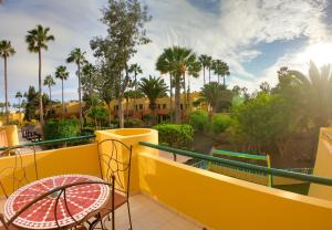 a balcony with a table and chairs and palm trees at Drago 1 Atlantic Garden apartment in Corralejo