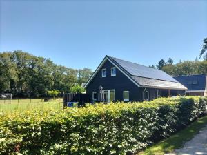 a black house in a field with flowers in front at De Heide in Wijnjewoude