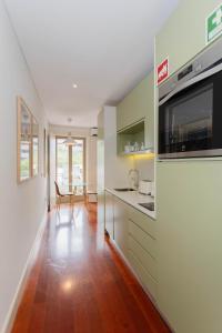 een keuken met groene kasten en een houten vloer bij Liiiving in Porto - Trindade Deluxe Studios in Porto