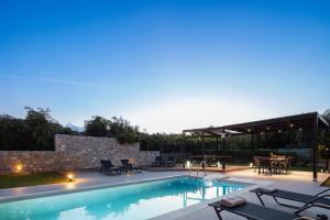 a swimming pool with a patio and a table and chairs at Villa Amalia in Áyios Vasílios
