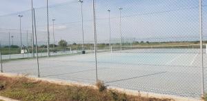 two tennis courts are seen through a fence at Villa Kalos in Marinagri Resort in Policoro