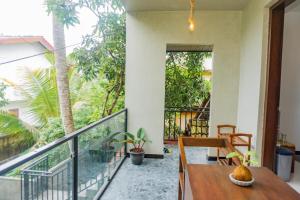 a balcony with a wooden table and chairs and trees at Surf Lavender in Weligama