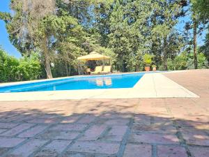 a swimming pool with a table and an umbrella at Villa Arbolada in San Lorenzo