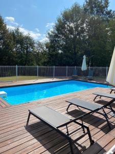 a swimming pool with two lounge chairs and an umbrella at Les gîtes de la Joubertie in Salon