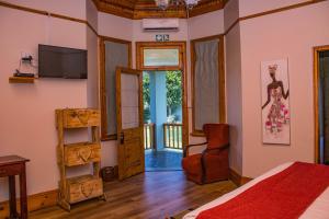 a bedroom with a bed and a tv on the wall at Presidents Boutique Lodge by Ilawu in Vryheid