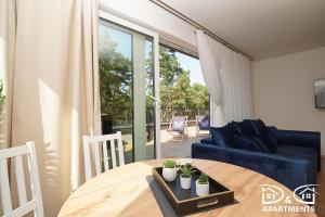 un salon avec une table et un canapé bleu dans l'établissement Pine Tree House 10 D&D Apartments, à Międzywodzie