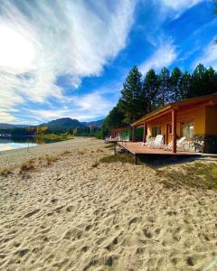 a house on a beach with chairs on the sand at Complejo Don Cirilo in Villa Pehuenia