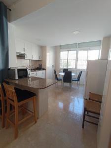 eine Küche mit einer Theke mit Stühlen und einem Tisch in der Unterkunft Blue Day Solo Familias in Puerto de Gandía