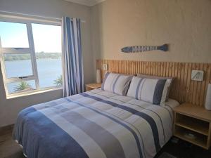 a bedroom with a bed and a large window at Be Lazy with a Sea View in Jeffreys Bay