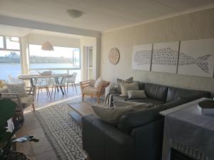 a living room with a couch and a dining room with a table at Be Lazy with a Sea View in Jeffreys Bay