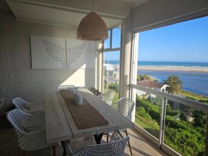 a dining room with a table and chairs and a large window at Be Lazy with a Sea View in Jeffreys Bay