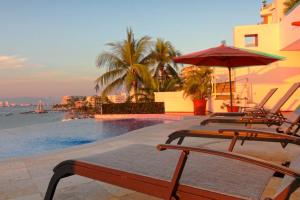 a group of chairs and an umbrella next to a pool at Two-Story Beachfront Oasis in Puerto Vallarta