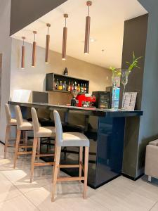 een bar met vier stoelen en een aanrecht in een kamer bij Promenade Soho Campos dos Goytacazes - OFICIAL in Campos dos Goytacazes