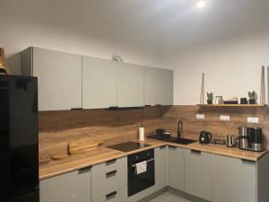 a kitchen with white cabinets and a wooden counter top at MoryńApartments R20 in Moryń