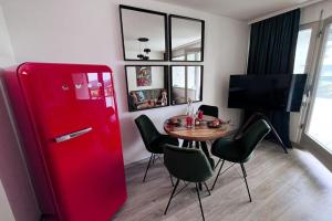 Cette chambre comprend un réfrigérateur rouge et une table avec des chaises. dans l'établissement Apartment mit Grünblick & Wintergarten im Schwarzwald, à Löffingen