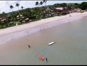 ein Strand mit zwei Personen und einem roten Boot im Wasser in der Unterkunft Villas Vovô Marcos - Beira Mar in São José da Coroa Grande + 8 Fotos