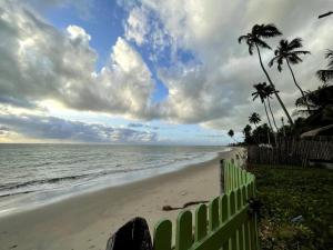 ein Strand mit einem Zaun und Palmen und dem Meer in der Unterkunft Villas Vovô Marcos - Beira Mar in São José da Coroa Grande
