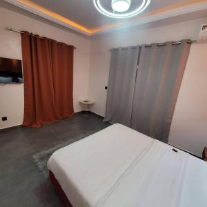 a bedroom with a white bed and orange curtains at Hotel maty in Sali Tapé