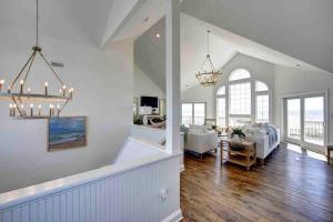 a large living room with white walls and wood floors at 8 Bed Oceanfront in OBX with Pool & Hot Tub in Frisco +50 photos