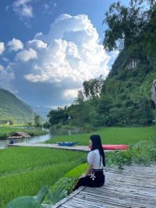 una mujer sentada en un puente mirando un río en Mai Chau riverside camping, en Mai Chau
