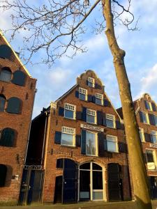 an old brick building with a tree in the foreground at Vintage appartement in Pakhuis Friesland in centrum in Leeuwarden
