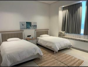 a bedroom with two beds and a window at Acacia Beach Villa in Al Sharqiyah