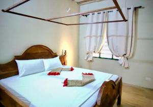 a bedroom with a large white bed with red flowers on it at The Tropinest bungalow in Nungwi