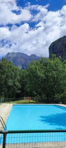 a large blue swimming pool with mountains in the background at Apartamento con vistas al Parque Nacional de Ordesa y Monteperdido in Torla