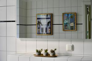 a bathroom with three mirrors and potted plants on a counter at ZUHAUSE AM MEER mit Sonnenbalkon in Strand- und Altstadtnähe in Warnemünde +20 photos