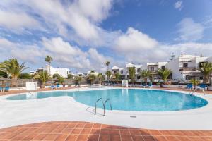 a large swimming pool in a resort with palm trees at Casa Lyrata in Costa Teguise