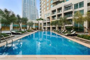 a large blue pool with chairs and buildings at Burj Khalifa & Fountain View- 5mn walk to Dubai mall -Stylish 1BDR Apartment in Dubai