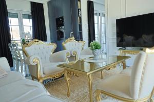 a living room with white chairs and a table and a tv at Vila Safra in Vrnjačka Banja