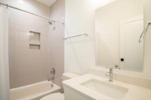 a white bathroom with a sink and a toilet at Luxury New Build with Oceanview - Go with the Flo 1 in Carolina Beach