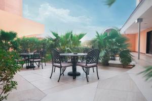 a patio with tables and chairs and palm trees at Boudl Al Maidan in Hafr Al Baten