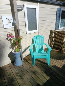 ein blauer Schaukelstuhl auf einer Terrasse mit einer Topfpflanze in der Unterkunft "Bungalow familial à Saint-Brevin-les-Pins avec piscine partagée" in Saint-Brevin-les-Pins