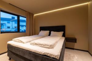 a bedroom with a bed with white sheets and a window at Aurora Escape in Tromsø