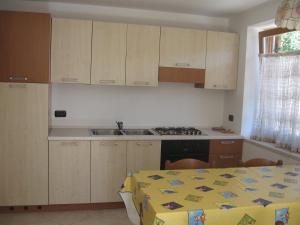 a kitchen with white cabinets and a table with a table cloth at Casa Franca in Cavalese