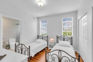 2 camas en un dormitorio con paredes blancas y suelo de madera en Fantastic Townhouse Beach Access Resort Amenities!, en Hallandale Beach 17 fotos más